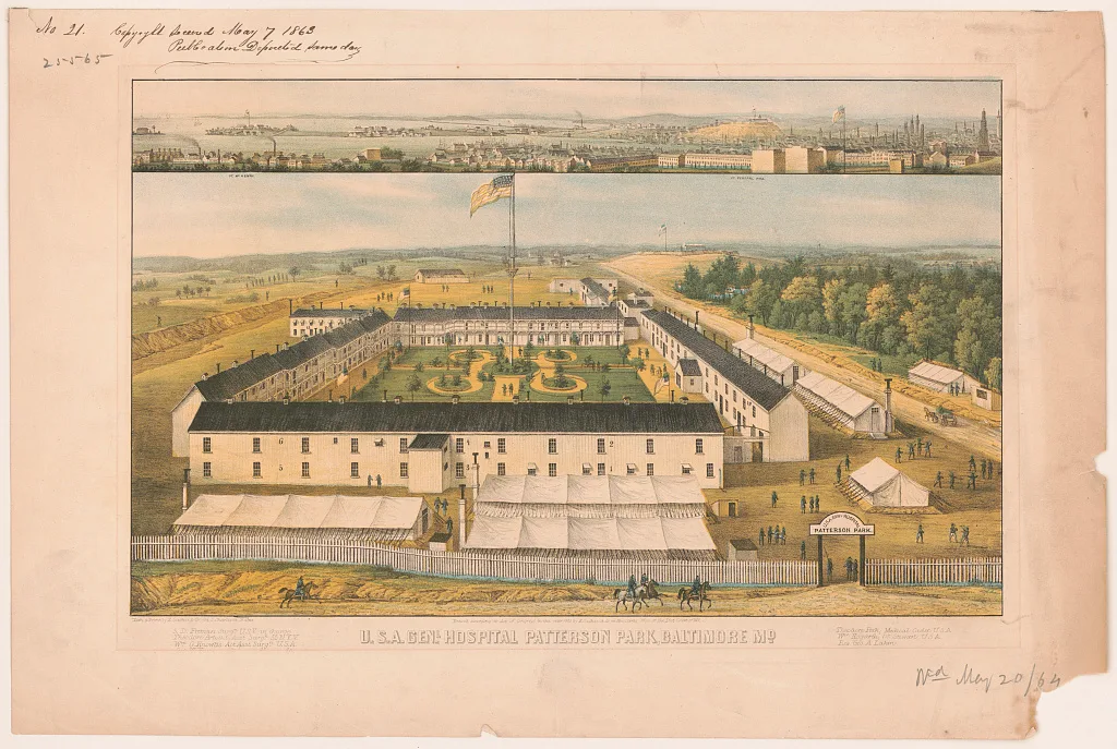 A hand-colored panoramic print shows the U.S.A. General Hospital at Patterson Park, with long white barracks arranged around a formal garden and flagpole, plus canvas tents and tiny figures scattered across the grounds. In the background, Baltimore’s skyline and harbor stretch across a hazy horizon, with the warm tones of the paper and print giving it an aged, archival look.